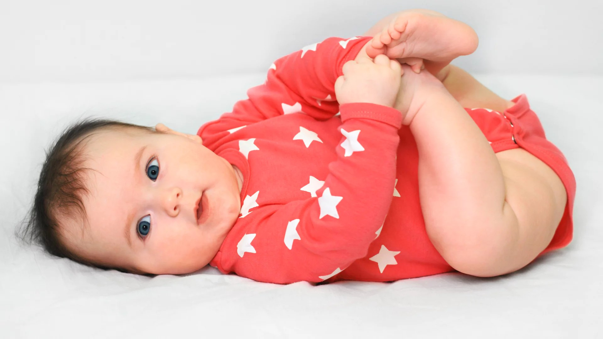 Baby in rotem Body mit weißen Sternen